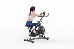 Woman exercising on a stationary bike in a home setting with text 'Real Comfortable Riding Feeling'.