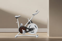 White exercise bike on a wooden floor with text about calorie burning and workout benefits.