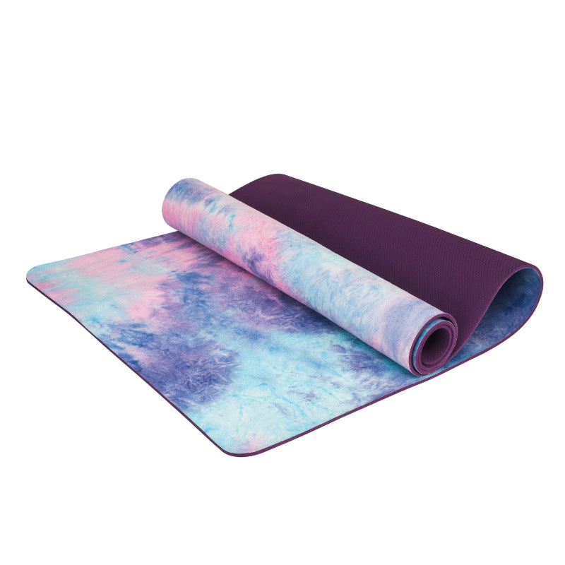 Two yoga mats, one rolled and one flat, with a tie-dye pattern on a white background.